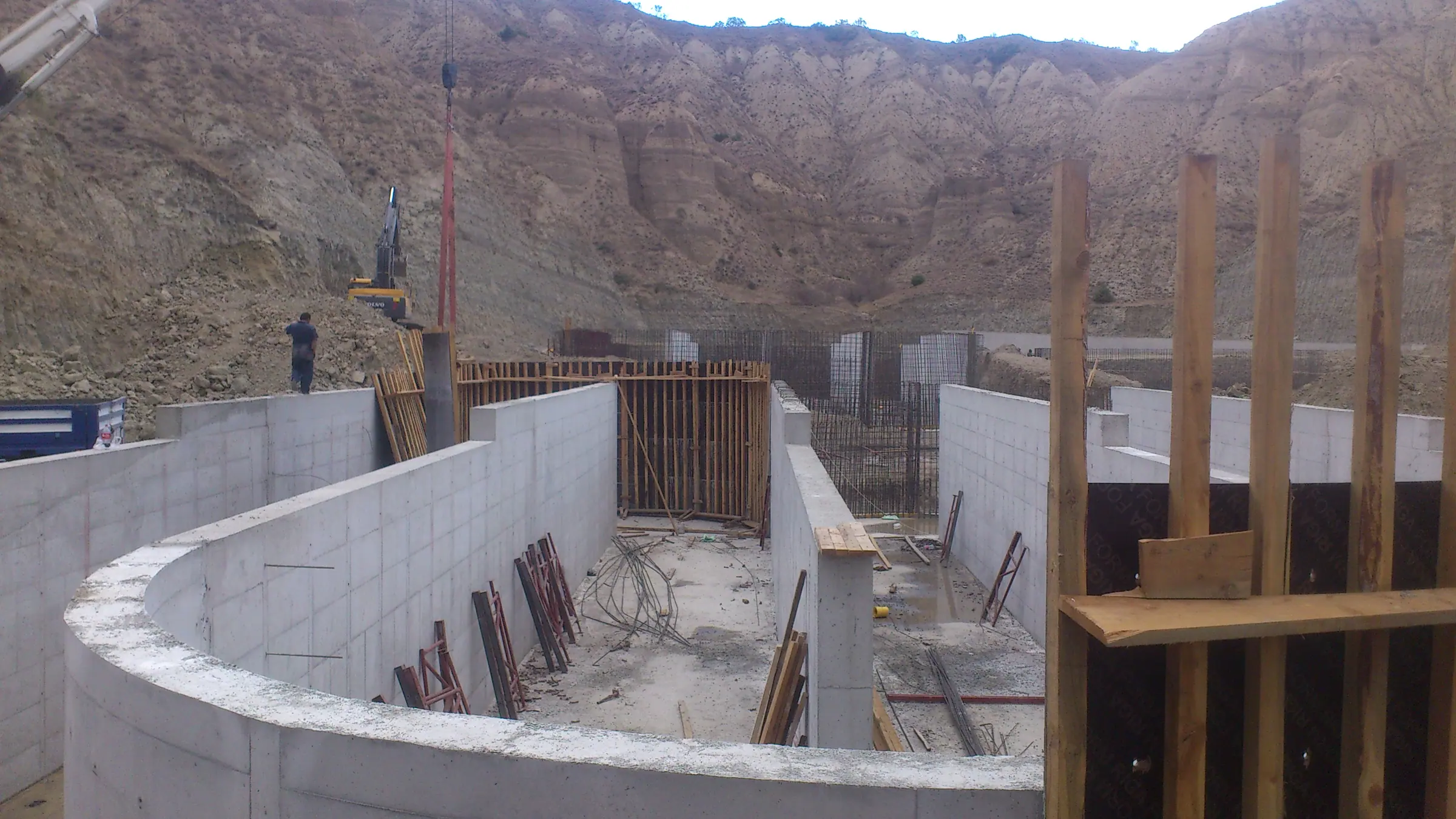 Eğrisel perde, dikdörtgen betonarme havuz duvarları, kırmızı kalıp destekleri ve arka planda ekskavatör