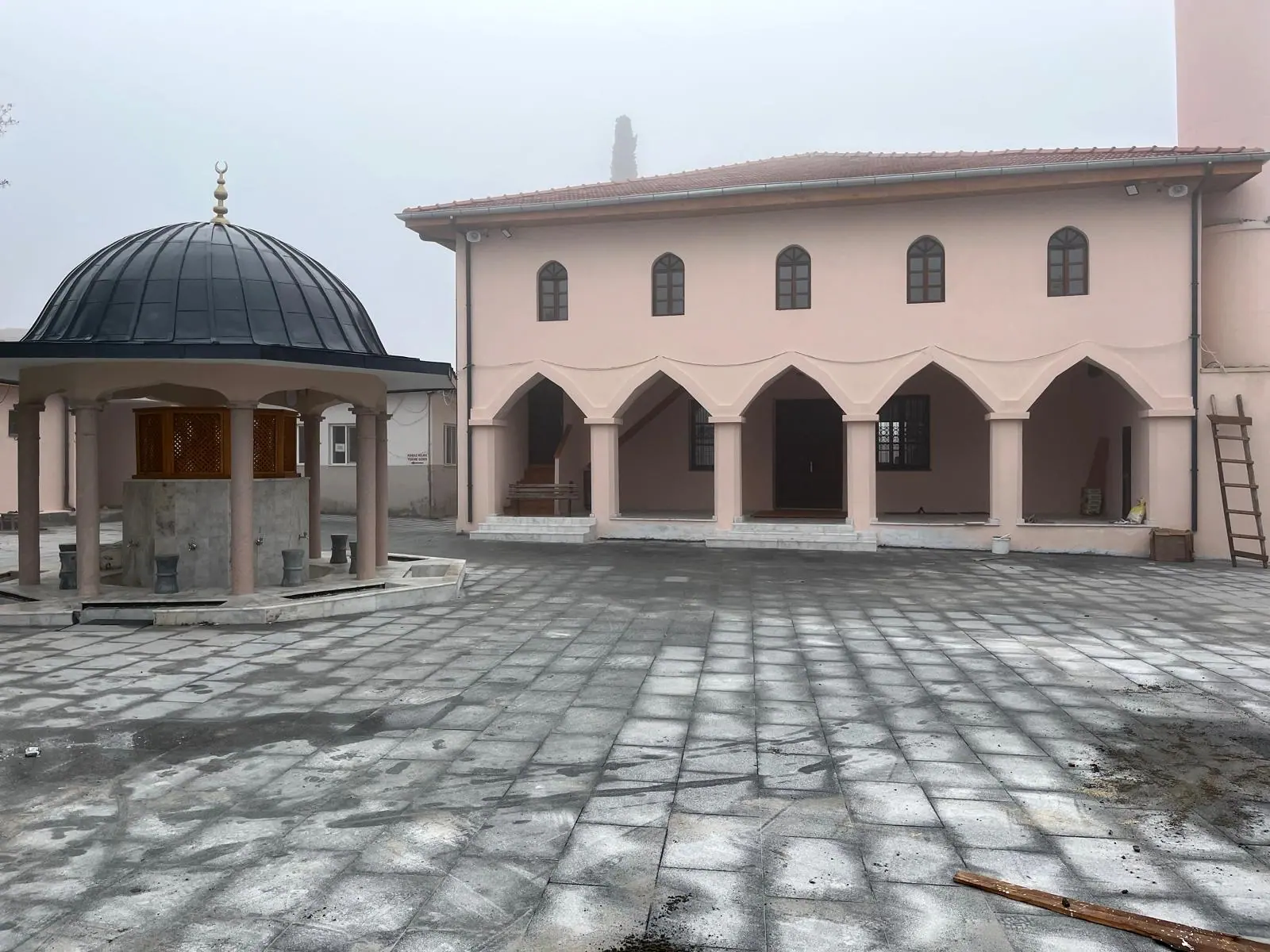 Somon boyalı cami cephesi, beş gözlü kemerli revak, plak kaplı avlu ve kubbeli şadırvan