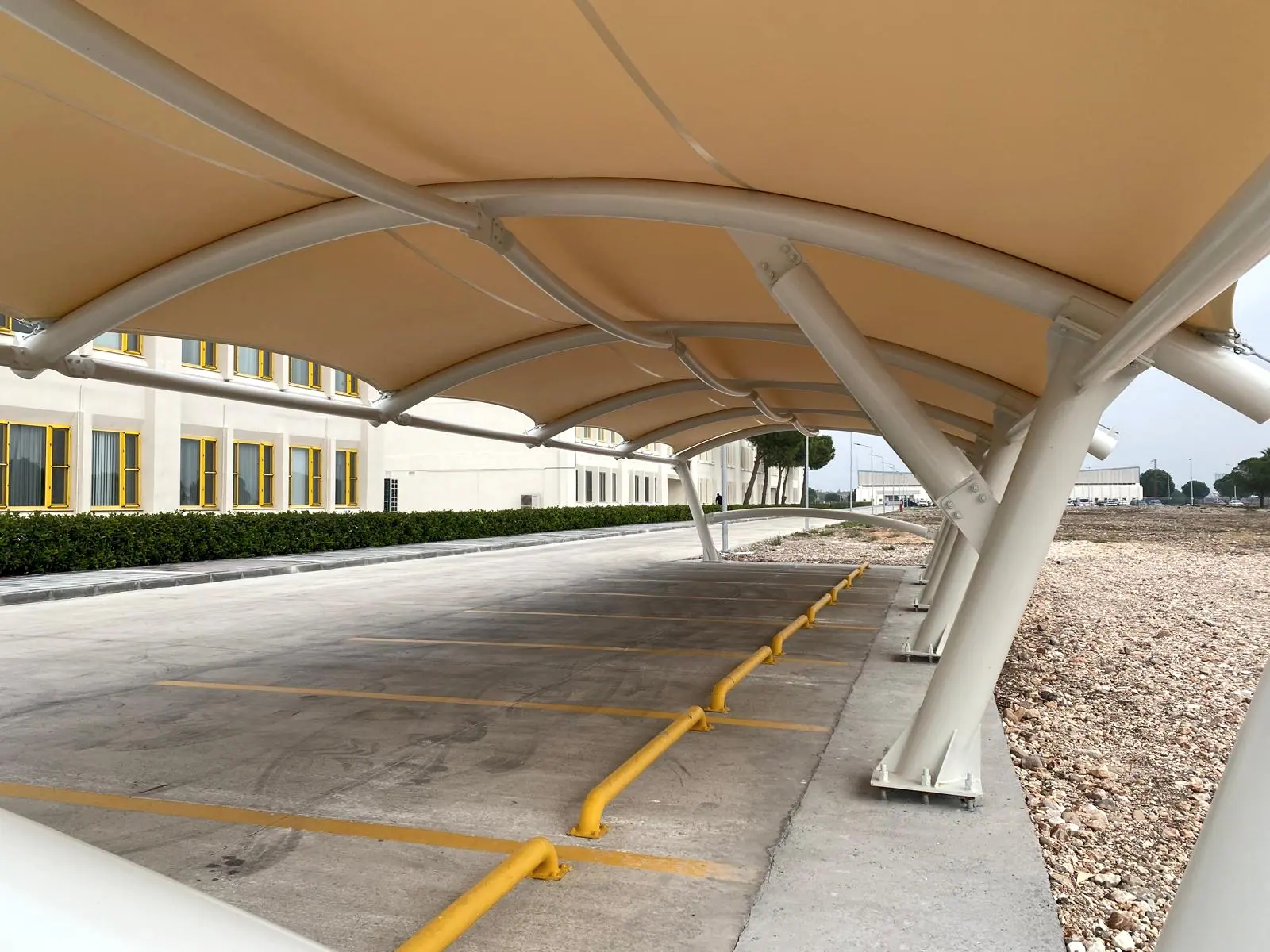 Germe örtünün alt yüzü, kavisli çelik kaburgalar ve altındaki sarı çizgili beton otopark şeridi