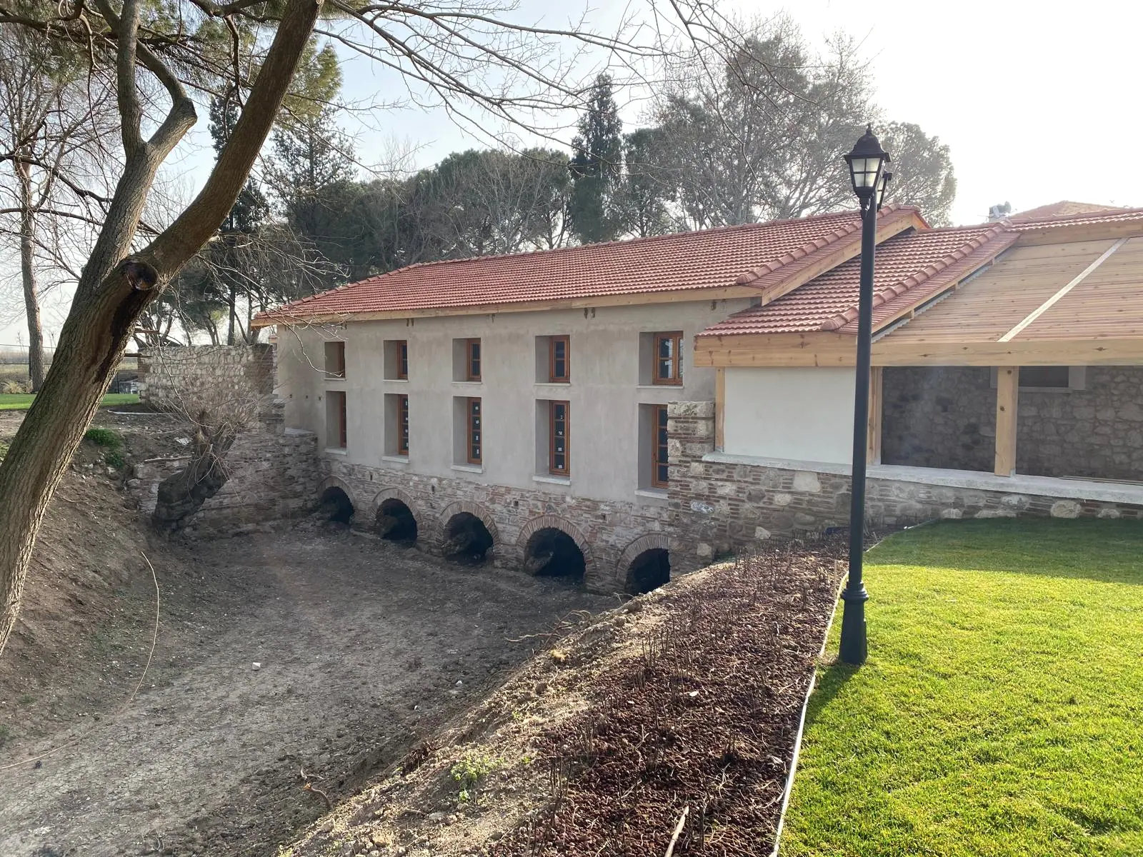 Kiremit çatılı sıvalı cephe, ahşap doğramalı pencere dizisi ve subasmanda tuğla kemerli su çıkışları